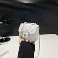 Mini white quilted chain bag with gold camellia buckle shown held in hand gracefully - White
