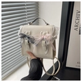 Close-up of cream lace handbag with elegant checkered and pink bow details - White