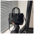 Close-up of minimalist black leather handbag showing smooth texture and golden metal hooks - Black