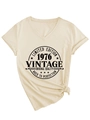 Detail van beige T-shirt met V-hals, vintage 1976 print en een stijlvolle knoop in de zoom - S / Zand (Zwart Lettertype)