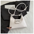Bolso de mano blanco trenzado con hebilla de lazo plateado sobre fondo de blazer negro - Blanco