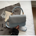 Detail of blue handbag with woven handle and wavy fabric flap featuring gold buckle - Blue