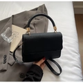 Detailed view of the black crossbody bag showing textured flap and woven handle craft - Black