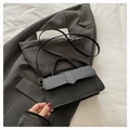 Chic black PU leather handbag with gold hardware and geometric flap on a stylish suit background - Black
