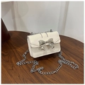 Dettaglio borsa a tracolla color crema con grande fiocco in metallo argento su tavolo legno - Bianco Sporco