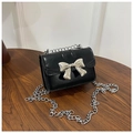 Dettaglio di una mini borsa nera con fiocco in metallo argento e sottile catena - Nero