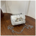 Dettaglio mini borsa argento metallizzato con fiocco grande e catena sottile su tavolo in legno - Argento