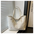 Dettaglio di ricamo a farfalla e trama di lettere goffrate su borsa tote beige - Bianco
