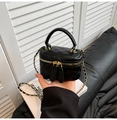 Quilted black mini vanity bag with chain strap and gold hardware held by a model - Black