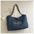 Detailansicht der Hello-Stickerei und weißen Nähte auf blauer Denim-Tasche - Blau