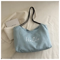 Detailaufnahme der hellblauen Denim-Tasche mit weißem Hello-Stick und schwarzen Trägern - Hellblau