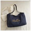 Detail der goldenen Hello-Stickerei auf blauer Denim-Tasche mit weißen Kontrastnähten - Dunkelblau