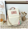 Détail du grand sac à dos crème avec bretelles roses contrastées et pompon coloré - Blanc