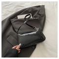 Elegante borsa a tracolla in pelle verniciata nera lucida su una giacca grigia formale - Nero