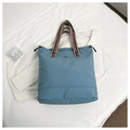Close-up of casual grey-blue tote bag with colorful striped handles and side drawstrings - Blue