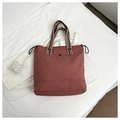 Detail of brick red tote bag with striped handles and drawstring closure on white textile - Pink