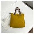 Detail of yellow nylon tote bag featuring red and blue striped webbing handles and logo - Dark Yellow