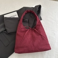 Minimalist burgundy suede tote bag with a bow tie detail in a high-end setting - Burgundy