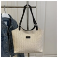 Detail of woven straw tote bag texture with black straps and fashion logo patch - Black