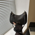 Minimalist black crescent shoulder bag featuring woven texture and golden bow detail - Black