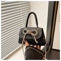 Detailed view of black mini crossbody bag featuring a sparkling rhinestone bow and chain - Black