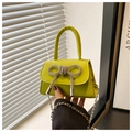 Detail of neon green mini bag with rhinestone bow and silver chain strap held by hand - Green