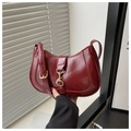Detailed close-up of dark red crescent shoulder bag with golden metallic hardware accents - Red