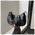 Detail view of glossy black crescent underarm bag featuring a metallic gold buckle closure - Black