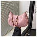 Detailed shot of pink leather crescent bag featuring vintage gold hardware and textured finish - Pink