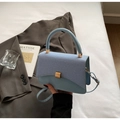 Detail of light blue textured crossbody bag with gold buckle and leather handle - Blue