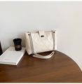 Detail of the diamond-quilted pattern and metallic twist lock on the cream chain bag - Off White