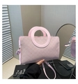 Dettaglio borsa in pelle rosa chiaro con manico circolare e tracolla sottile su libri - Rosa
