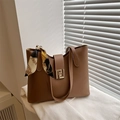 Detail van bruine leren shopper met gouden gesp en decoratieve zijden sjaal aan de greep - Tan