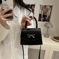 Mini black crossbody bag with a golden bow buckle in a minimalist aesthetic - Black