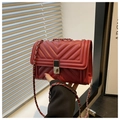 Close-up of deep red quilted bag with silver twist-lock and metal chain strap - Red