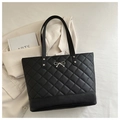 Detail of black quilted tote bag with metallic bow and elegant faux leather texture - Black