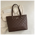 Detail of dark brown quilted tote bag with silver bow accent and rivet reinforcements - Brown