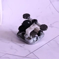Detailansicht eines Spieluhr-Mechanismus mit silbernem Sockel und schwarzen Zahnrädern - Silber
