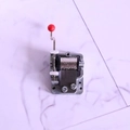 DIY hand-cranked music box mechanism with silver metal gears and red knob handle - Hand Crank Style