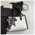 Detail view of monochrome snakeskin tote with fashion logo and decorative heart scarf - Black