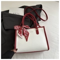 Detail of snake skin texture handbag with red silk scarf bow and gold logo branding - Red