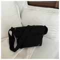 Detail of minimalist black crossbody bag with metallic logo on a soft white bed - Black