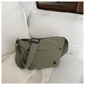 Detailed macro view of the grey-green nylon crossbody bag with metal buckle on a white bed - Green