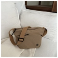 Detail of khaki nylon crossbody bag with adjustable strap on white bedding backdrop - Khaki