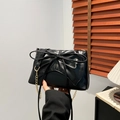 Elegant black tote bag with oversized bow design and gold chain strap in hand - Black