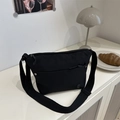Minimalist black nylon crossbody bag with adjustable wide strap shown in lifestyle setting - Black