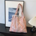 Rosafarbene Stickerei-Tasche mit Spitzensaum und Schleife in Lifestyle-Szenerie - Rosa