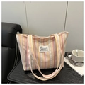Detailopname van meerkleurige gestreepte canvas shopper met modieus label en stevige handvatten - Roze