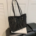 Black minimalist tote bag featuring a unique crinkled texture and golden metal rivets - Black