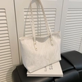 Chic beige tote bag with cloud-like pleats and gold rivets on a sleek black bench - Off White